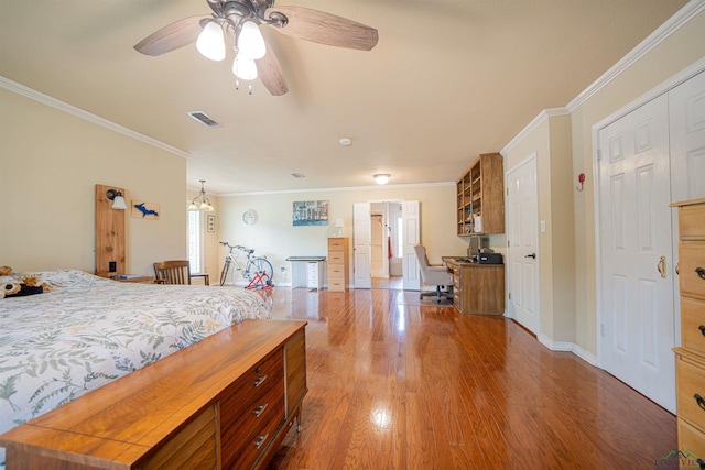 bedroom with a closet, crown molding, ceiling fan with notable chandelier, and dark hardwood / wood-style floors