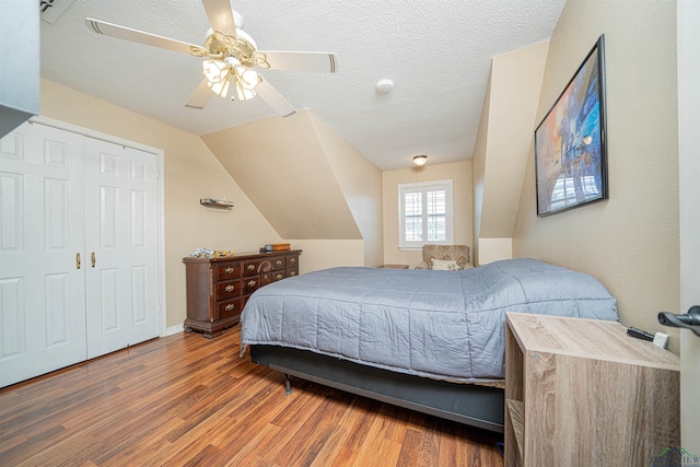 bedroom featuring a textured ceiling, lofted ceiling, dark hardwood / wood-style floors, a closet, and ceiling fan