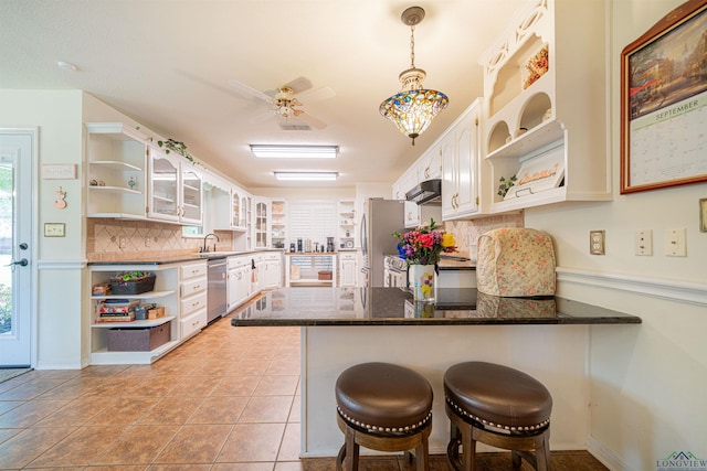 kitchen with a breakfast bar, kitchen peninsula, appliances with stainless steel finishes, and white cabinetry