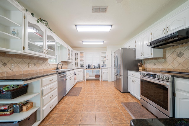 kitchen with light tile patterned floors, appliances with stainless steel finishes, white cabinets, and tasteful backsplash