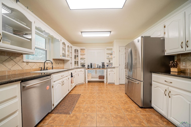 kitchen with white cabinetry, stainless steel appliances, and dark stone counters