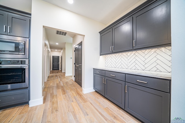 kitchen with backsplash, stainless steel appliances, and light hardwood / wood-style floors