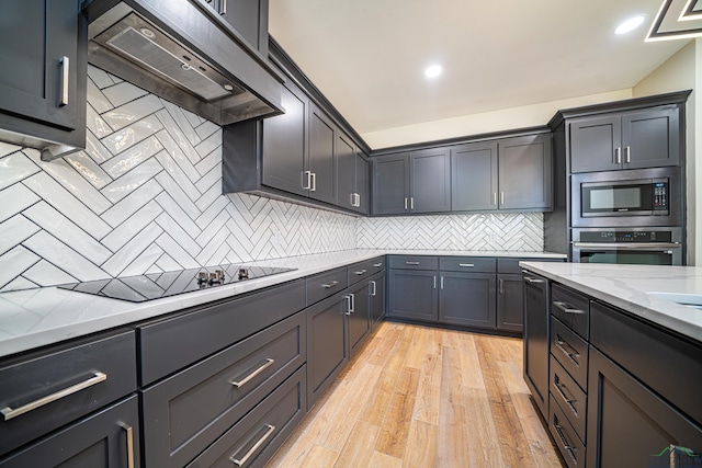 kitchen with exhaust hood, decorative backsplash, light stone countertops, light wood-type flooring, and stainless steel appliances