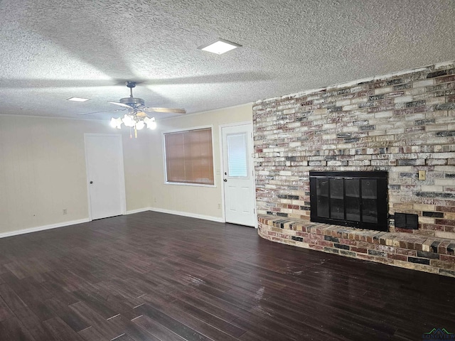 unfurnished living room featuring a textured ceiling, dark hardwood / wood-style floors, a brick fireplace, and ceiling fan