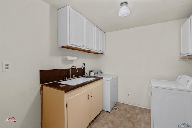 clothes washing area with washer and dryer, sink, and cabinets