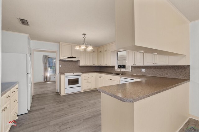 kitchen with sink, hanging light fixtures, kitchen peninsula, hardwood / wood-style floors, and white appliances