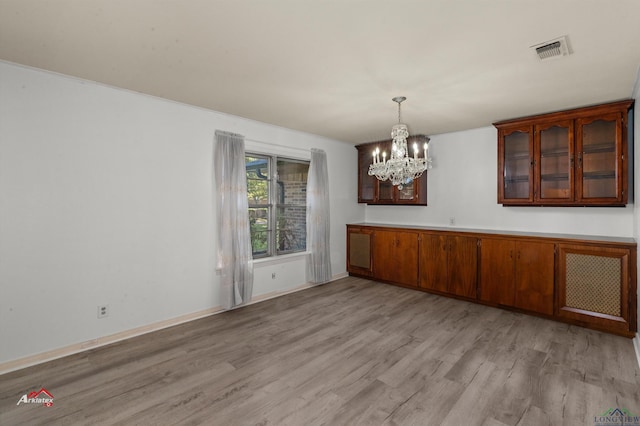 unfurnished dining area with light wood-type flooring and a notable chandelier