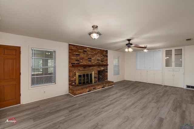 unfurnished living room with hardwood / wood-style flooring, ceiling fan, and a fireplace