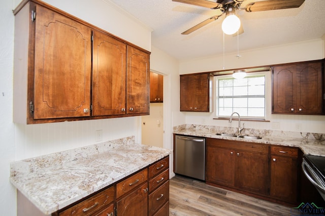 kitchen featuring light stone countertops, light wood-style floors, ceiling fan, a sink, and appliances with stainless steel finishes