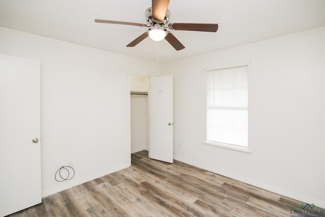 unfurnished bedroom featuring baseboards, ceiling fan, wood finished floors, and a closet