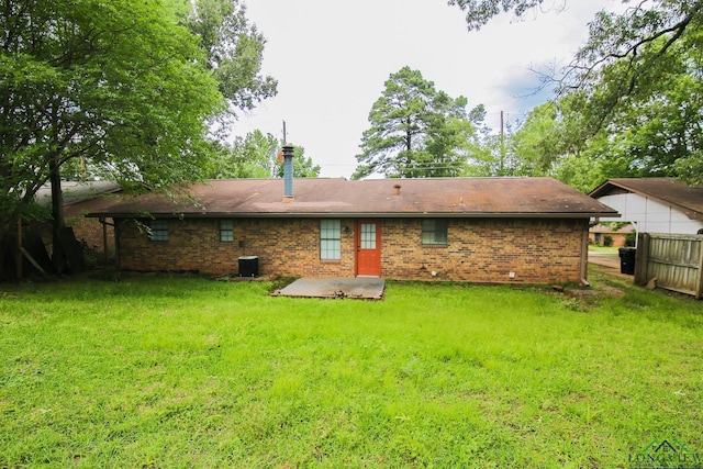 rear view of house featuring fence, central AC, brick siding, a patio area, and a lawn