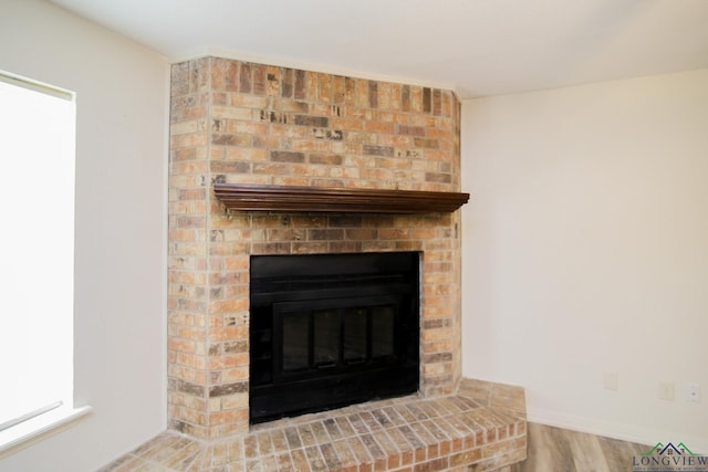 interior details with baseboards, a brick fireplace, and wood finished floors