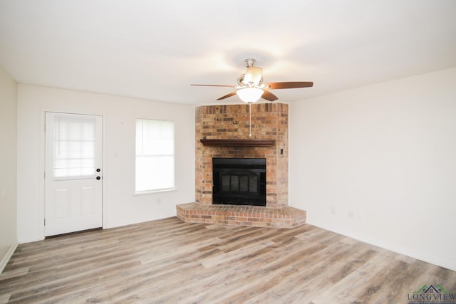 unfurnished living room featuring a ceiling fan, wood finished floors, and a fireplace