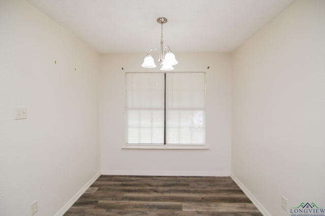 spare room featuring baseboards, wood finished floors, and a chandelier