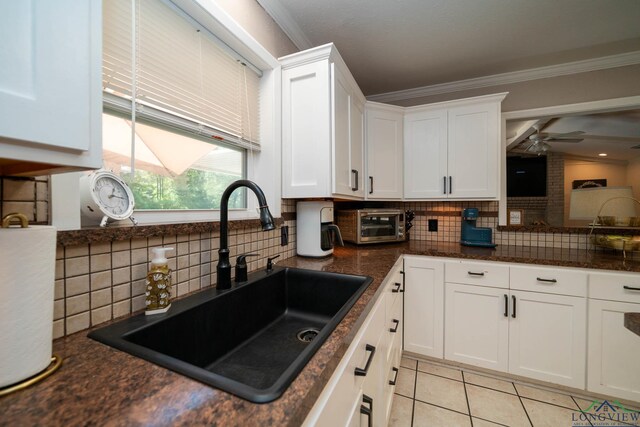 kitchen with ornamental molding, ceiling fan, sink, light tile patterned floors, and white cabinets