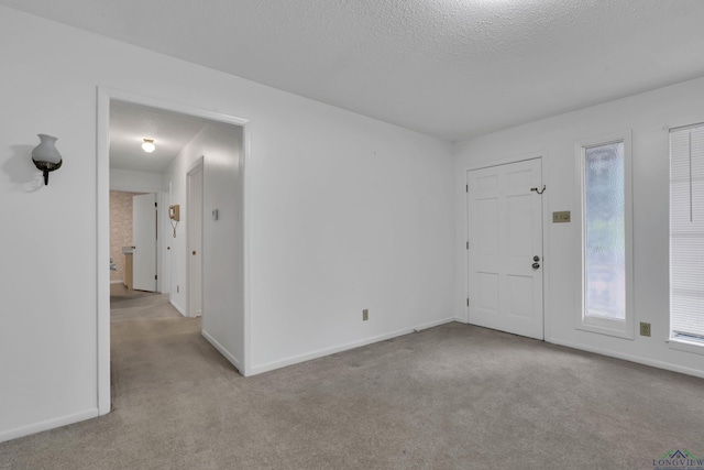 carpeted empty room with a textured ceiling and baseboards