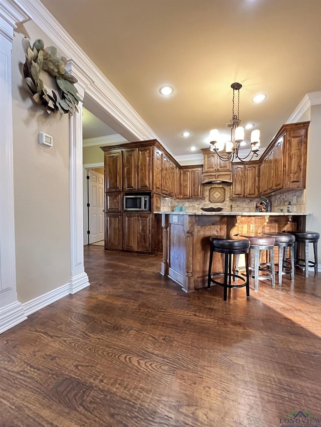 kitchen with stainless steel microwave, crown molding, decorative light fixtures, dark hardwood / wood-style floors, and a notable chandelier