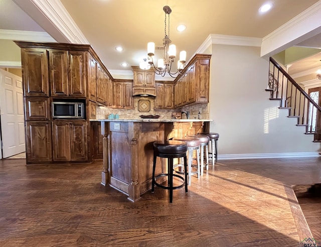 kitchen with backsplash, crown molding, hanging light fixtures, a notable chandelier, and light stone counters