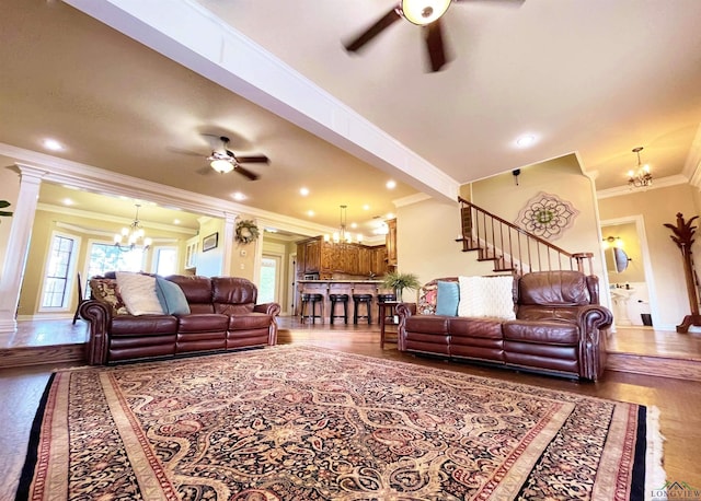 living room with ornate columns, ornamental molding, ceiling fan with notable chandelier, and hardwood / wood-style flooring