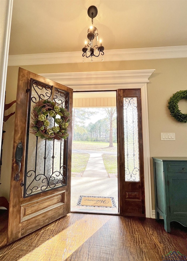 foyer entrance featuring a notable chandelier, wood-type flooring, and ornamental molding