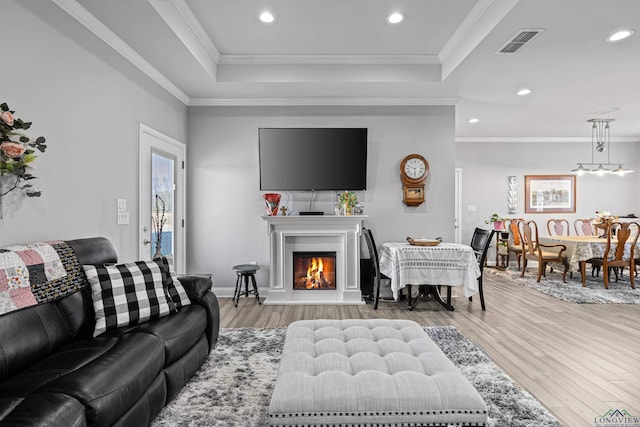 living room with a raised ceiling, crown molding, and hardwood / wood-style flooring