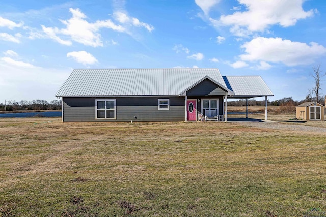 view of front facade with a carport, a front yard, and a storage shed