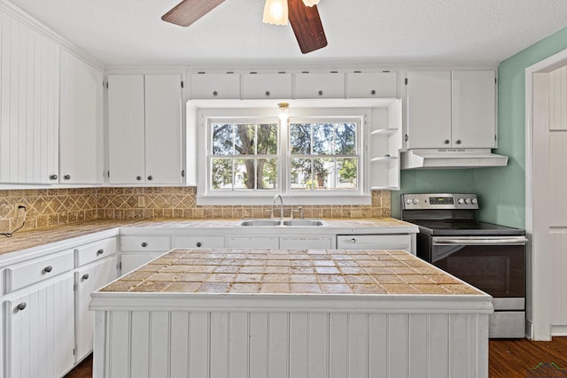 kitchen featuring stainless steel electric stove, a kitchen island, white cabinets, and sink