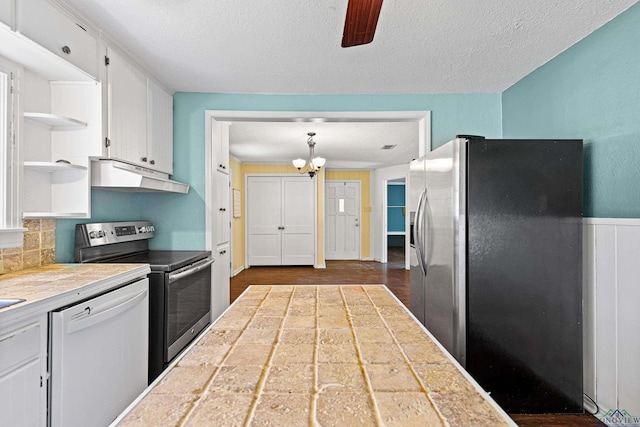 kitchen with decorative backsplash, appliances with stainless steel finishes, ceiling fan with notable chandelier, tile countertops, and white cabinetry