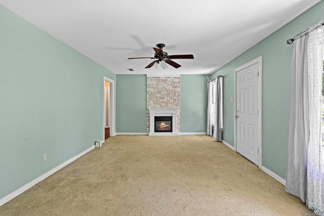 unfurnished living room featuring a fireplace, a wealth of natural light, light colored carpet, and ceiling fan