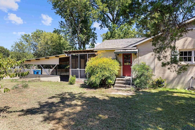 view of front of property with a carport, a sunroom, and a front lawn