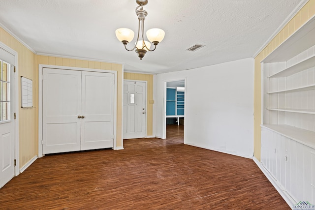 interior space with dark hardwood / wood-style floors, ornamental molding, a textured ceiling, and a chandelier