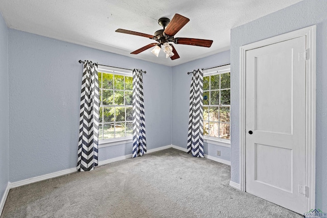 carpeted empty room with ceiling fan and a textured ceiling