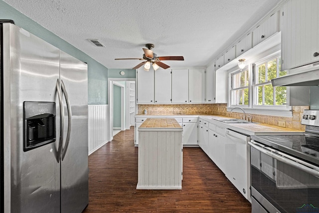 kitchen featuring tasteful backsplash, stainless steel appliances, dark wood-type flooring, a center island, and white cabinetry