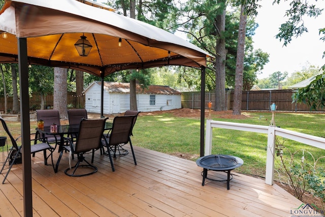 wooden deck featuring a gazebo, a shed, an outdoor fire pit, and a lawn