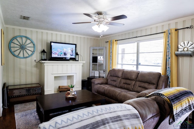 living room featuring ceiling fan, dark hardwood / wood-style floors, ornamental molding, and a textured ceiling