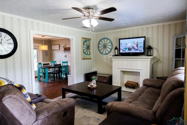 living room featuring ceiling fan, a brick fireplace, wood-type flooring, a textured ceiling, and ornamental molding