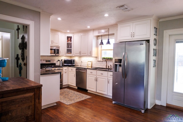 kitchen featuring pendant lighting, white cabinets, sink, dark hardwood / wood-style floors, and stainless steel appliances