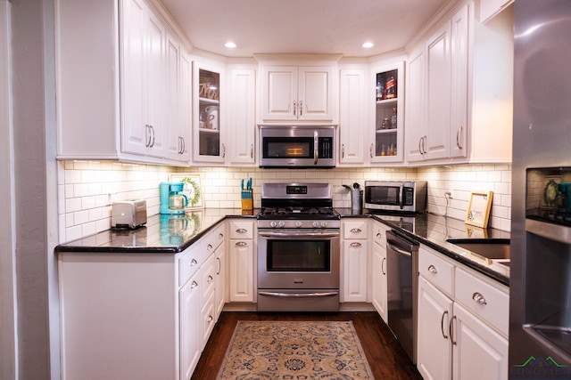 kitchen with appliances with stainless steel finishes, dark hardwood / wood-style flooring, tasteful backsplash, and white cabinetry