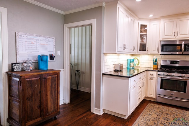 kitchen featuring decorative backsplash, appliances with stainless steel finishes, ornamental molding, dark wood-type flooring, and white cabinets