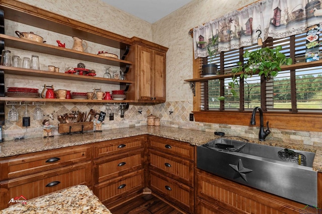 kitchen featuring dark hardwood / wood-style flooring, light stone countertops, and sink