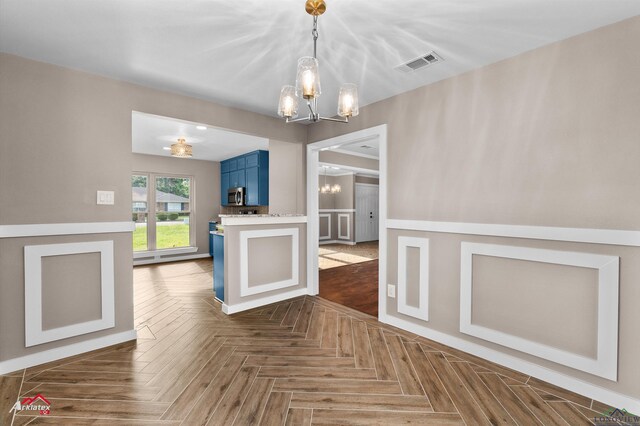 404 Pinewood, Marshall, TX 75672 - kitchen featuring blue cabinetry, a chandelier, stainless steel microwave, a wainscoted wall, and pendant lighting