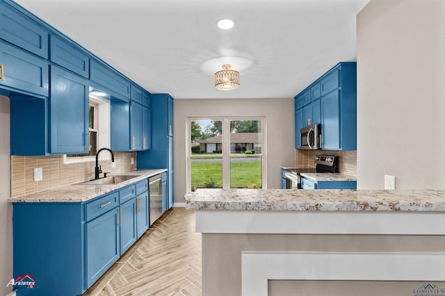 404 Pinewood, Marshall, TX 75672 - kitchen with appliances with stainless steel finishes, decorative backsplash, blue cabinetry, a peninsula, and light stone counters