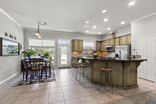 kitchen with appliances with stainless steel finishes, plenty of natural light, a breakfast bar area, and light tile patterned flooring