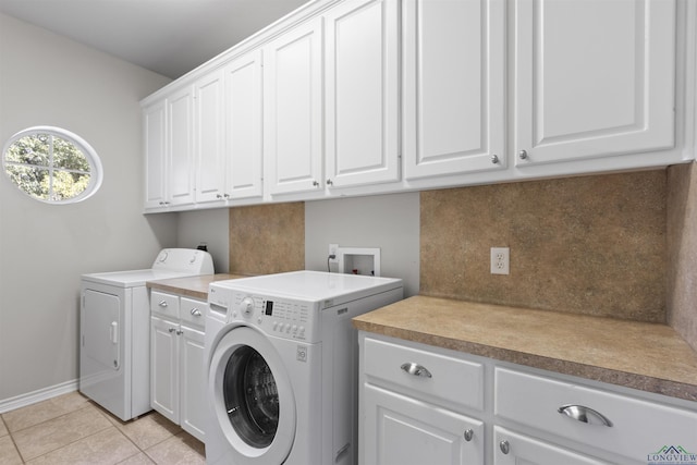 clothes washing area with washing machine and dryer, light tile patterned floors, and cabinets