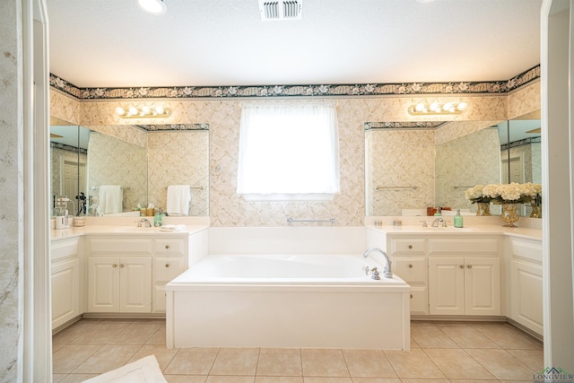 bathroom featuring a textured ceiling, tile patterned flooring, a tub, and vanity