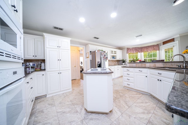 kitchen with sink, white cabinets, white appliances, and a center island