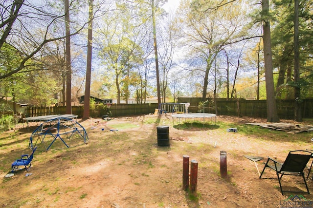 view of yard with a trampoline and a fenced backyard