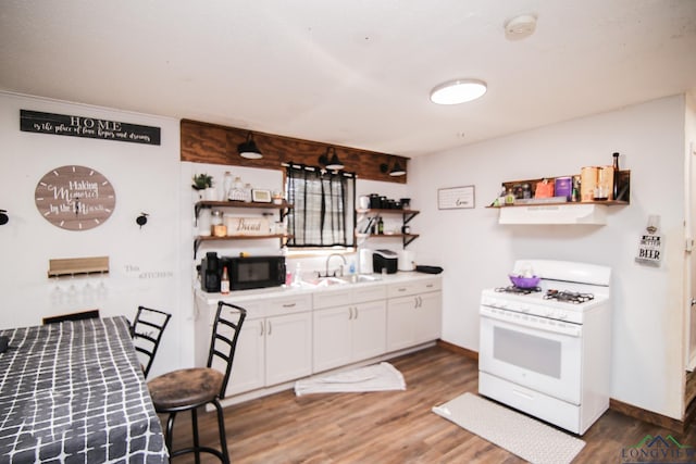 kitchen with open shelves, white range with gas stovetop, wood finished floors, and black microwave