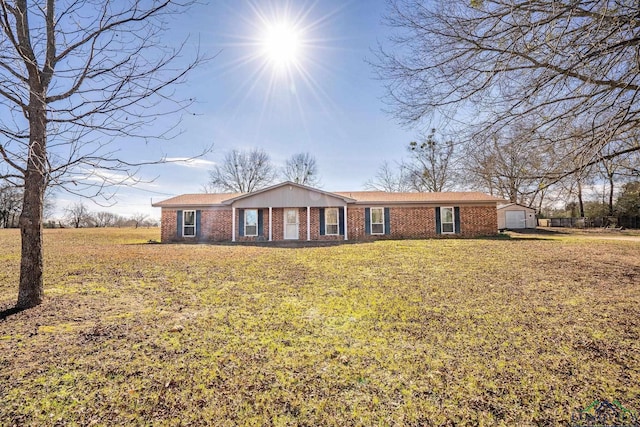 single story home featuring brick siding, an outdoor structure, and a front lawn