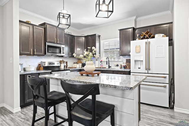 kitchen featuring dark brown cabinetry, appliances with stainless steel finishes, a breakfast bar, ornamental molding, and a sink